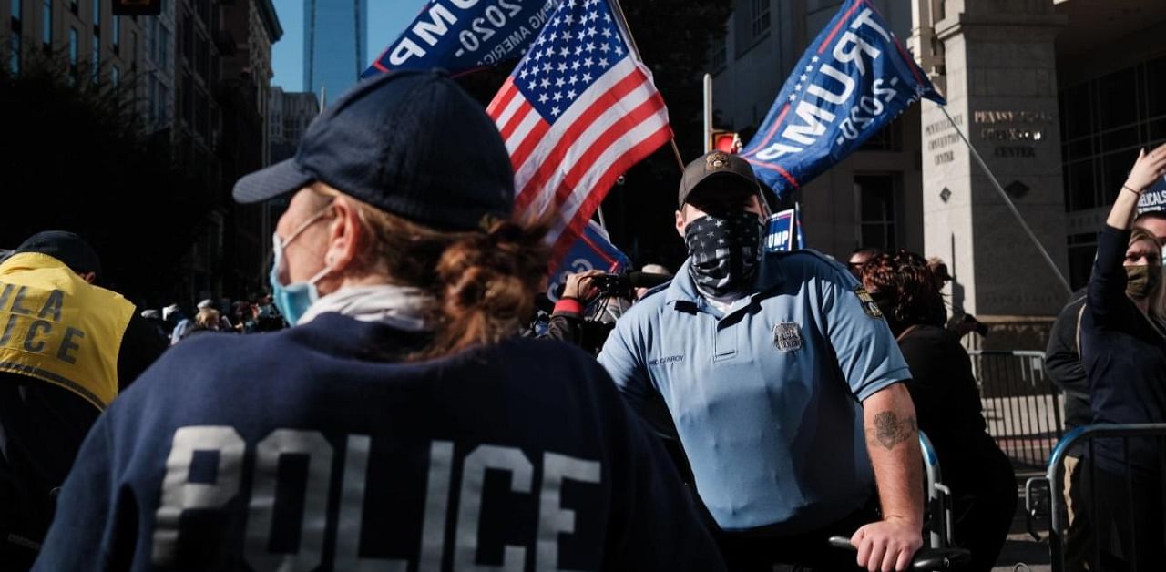 Police officers stand guard as Donald Trump supporters converge outside of the Philadelphia Convention Center as the counting of ballots continues in the state. Credit: AFP