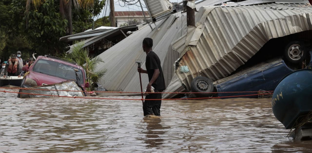 A resident walking through a flooded street looks back at storm damage caused by Hurricane Eta in Planeta. Credit: AP