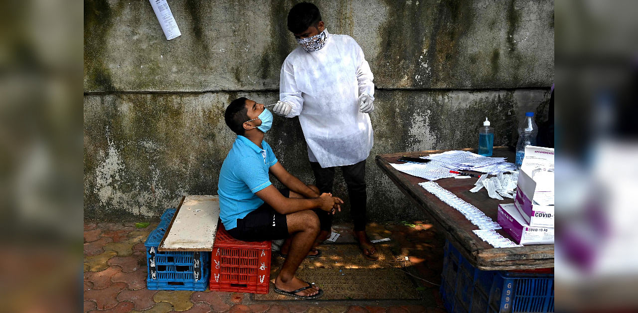 A health worker collects a swab sample during a medical screening for the Covid-19 Coronavirus, in Mumbai. Credit: AFP