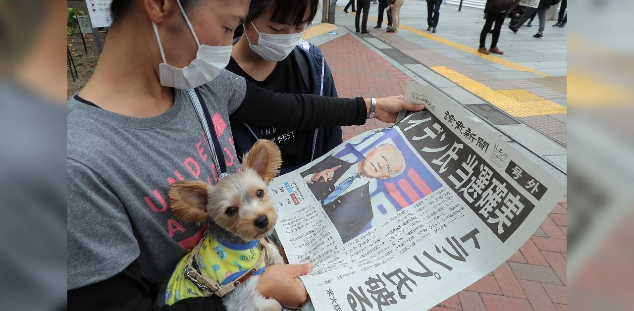 People read an extra edition of a newspaper reporting on US Democratic president elect Joe Biden's win in the US presidential election, in Tokyo. Credit: AFP Photo