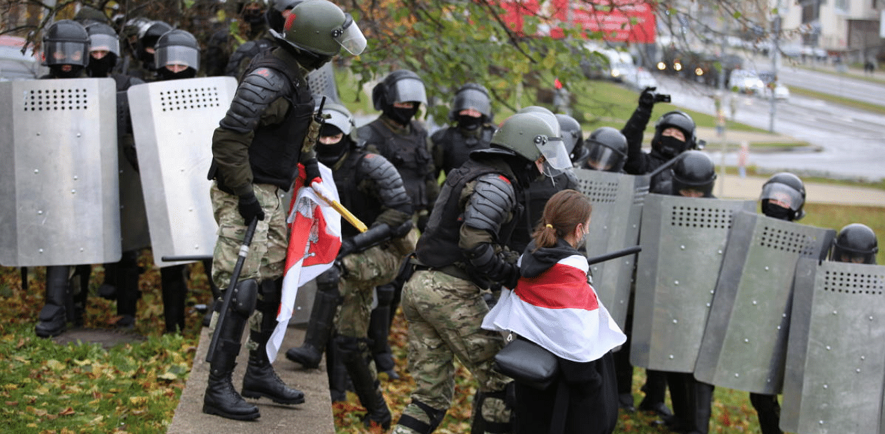 A woman wearing a historical white-red-white flag of Belarus is taken away by a law enforcement officer during a rally to reject the presidential election results in Minsk, Belarus. Credit: Reuters Photo