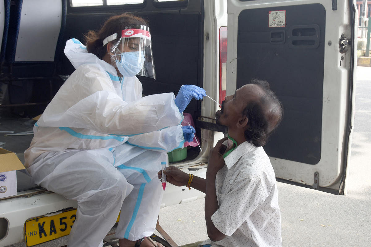 A healthcare worker take the swab sample from a man on Gubbi Thotadappa Road near the KSR Bengaluru railway station in the Majestic area. DH PHOTO/S K DINESH