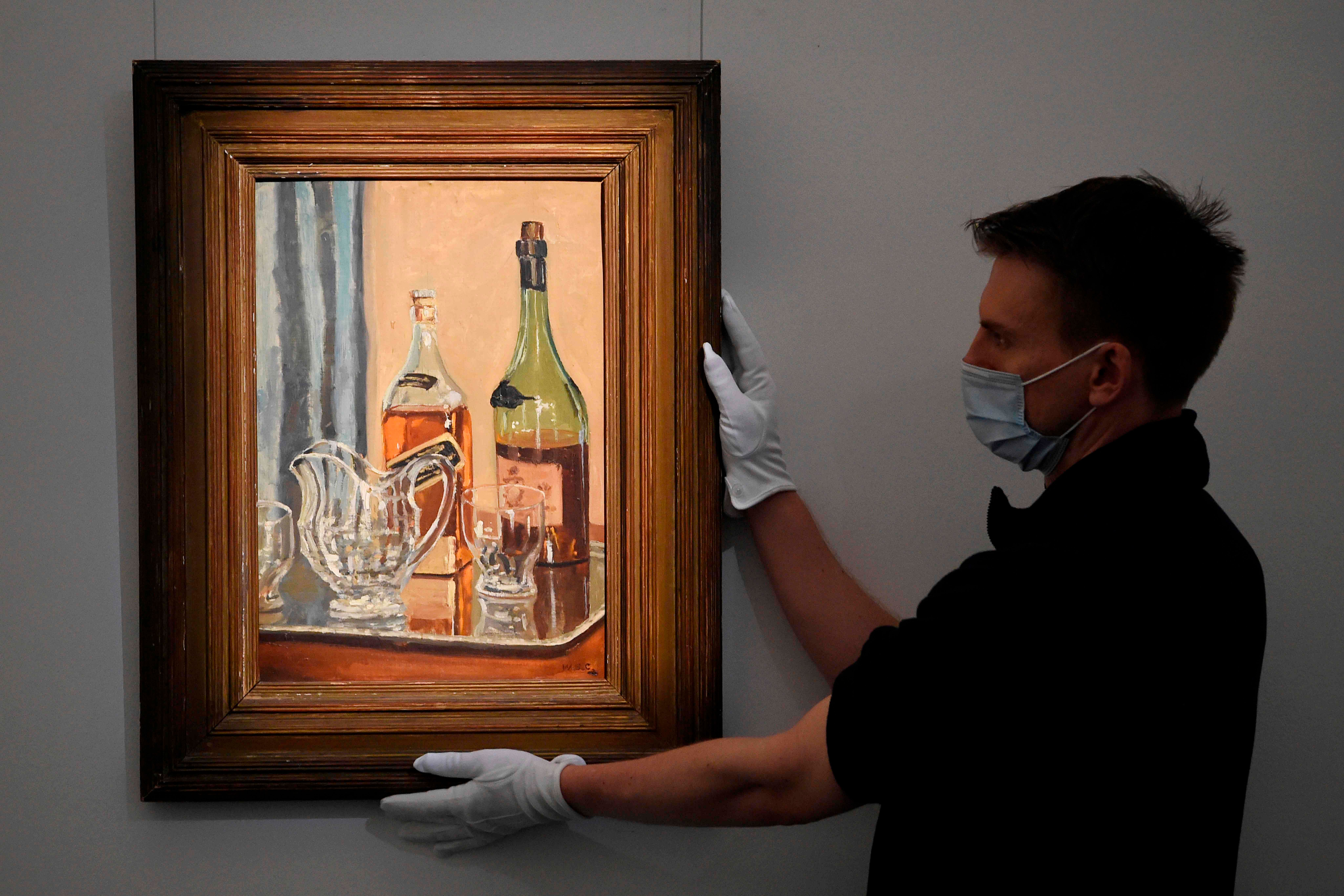 A member of staff poses with a painting by Britain's former prime minister Winston Churchill entitled "Jug with Bottles" at Sotheby's auction house in London on November 9, 2020. Credit: AFP Photo