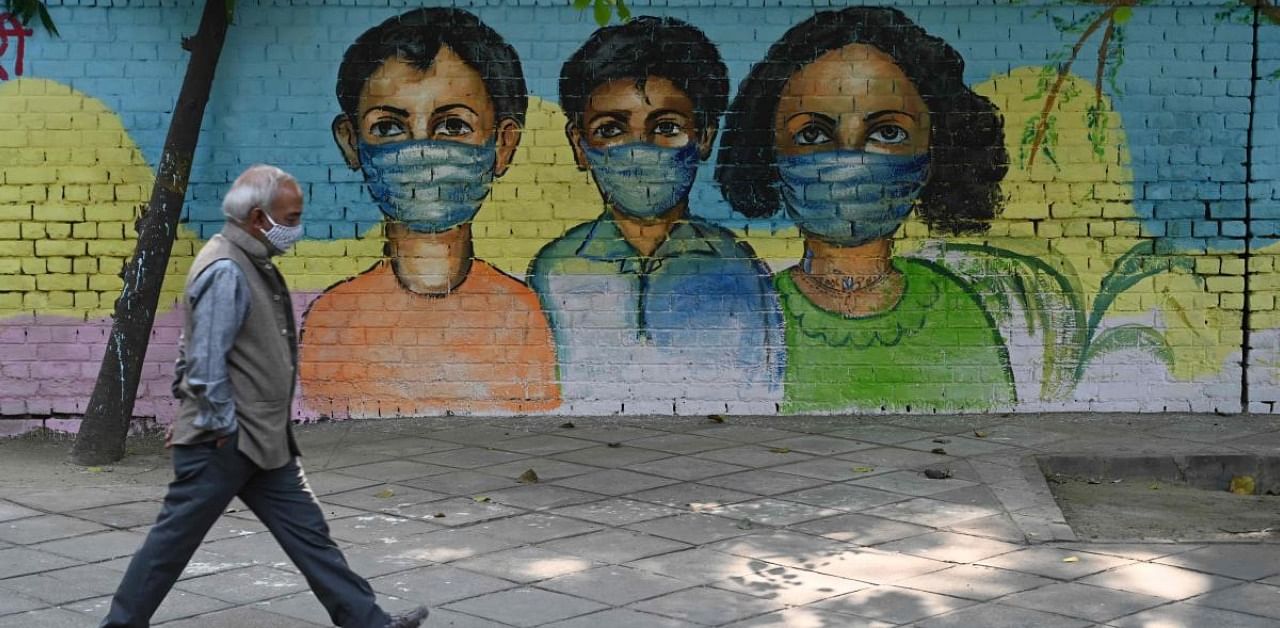 A man walks past in front of a mural depicting Covid-19 coronavirus awareness, in New Delhi on November 7, 2020. Credit: AFP Photo