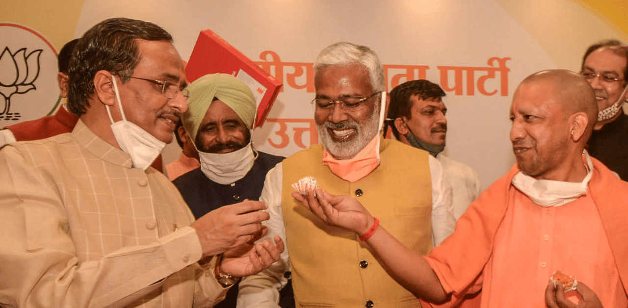 : Uttar Pradesh Chief Minister Yogi Aditiyanath, Dy CM Dinesh Sharma and UP BJP President Swatantra Dev Singh celebrate the party's win by-elections with sweets, at the party office in Lucknow, Tuesday, Nov. 10, 2020. Credit: PTI Photo