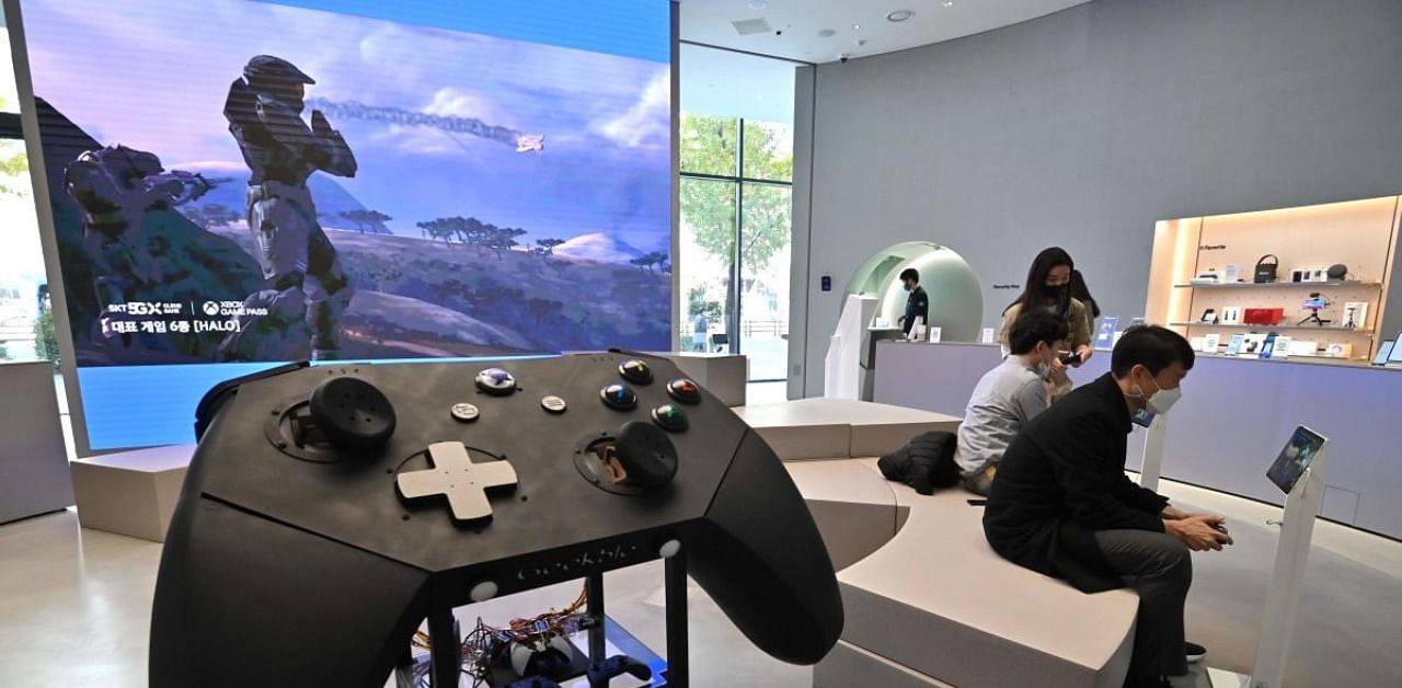 Visitors play games next to a big model of Microsoft's Xbox controller. Credit: AFP Photo