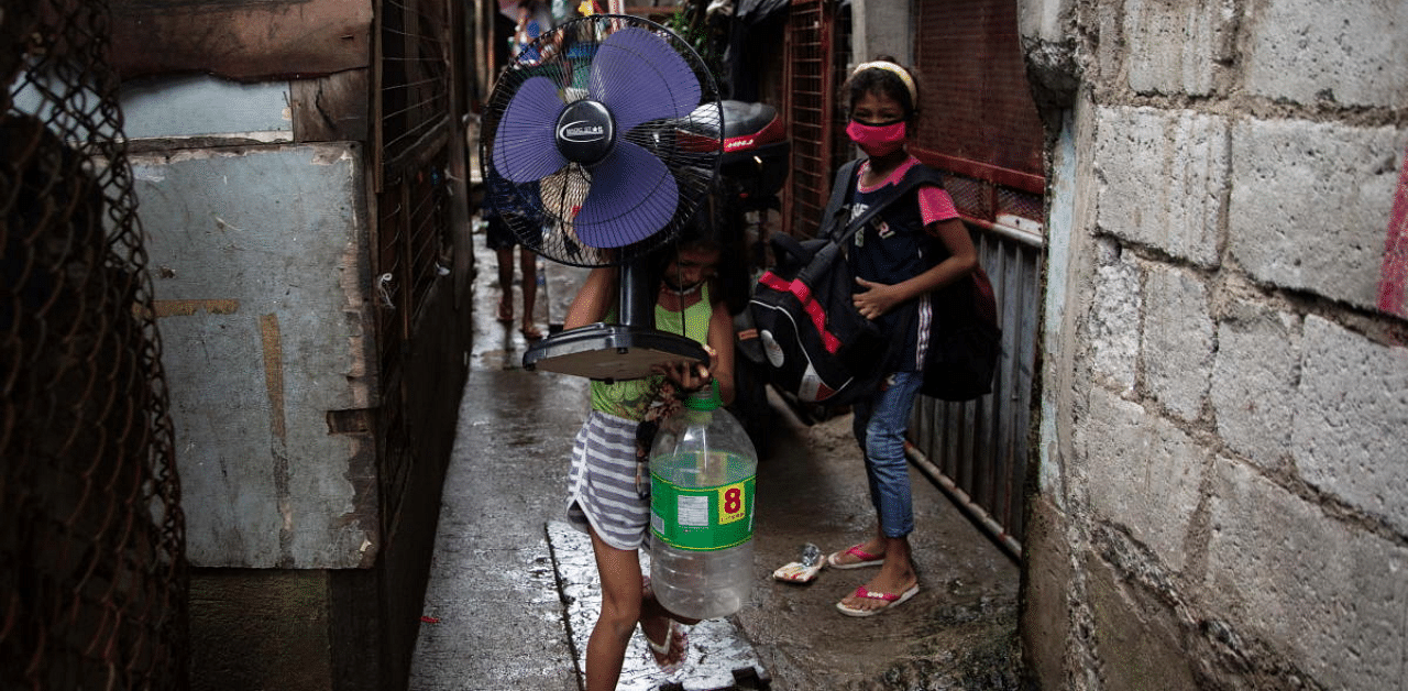 Girls carry an electric fan and bags of belongings as they evacuate from a coastal community ahead of Typhoon Vamco, in Sucat, Muntinlupa, Metro Manila, Philippines. Credit: Reuters Photo