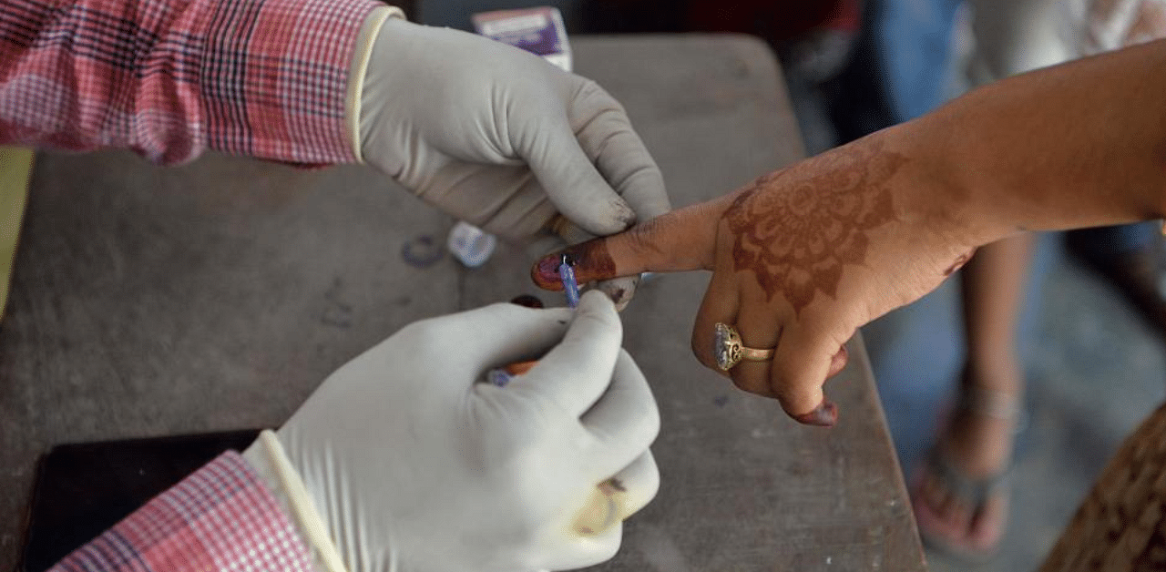 An electoral official marks a voter's finger with ink after casting her ballot during the last phase of Bihar state assembly elections at a polling station in Thakurganj on November 7, 2020. Credit: PTI Photo