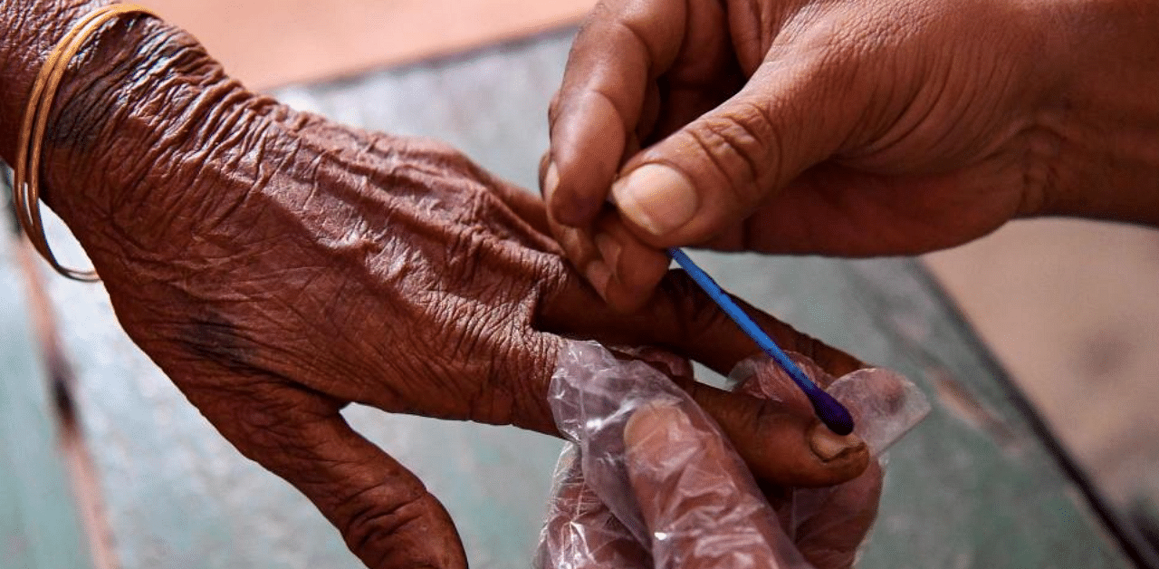 An electoral official mark a voter's finger with ink after casting her ballot for Bihar state assembly elections in a polling station in Patna on October 28, 2020. Credit: AFP Photo