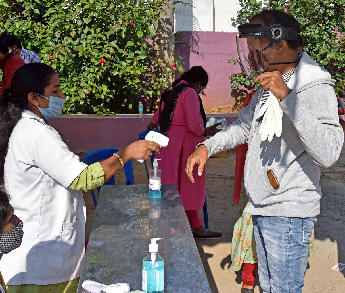 A healthcare worker checks the temperature of a voter during the RR Nagar assembly bypoll on November 3. DH PHOTO/M S MANJUNATH