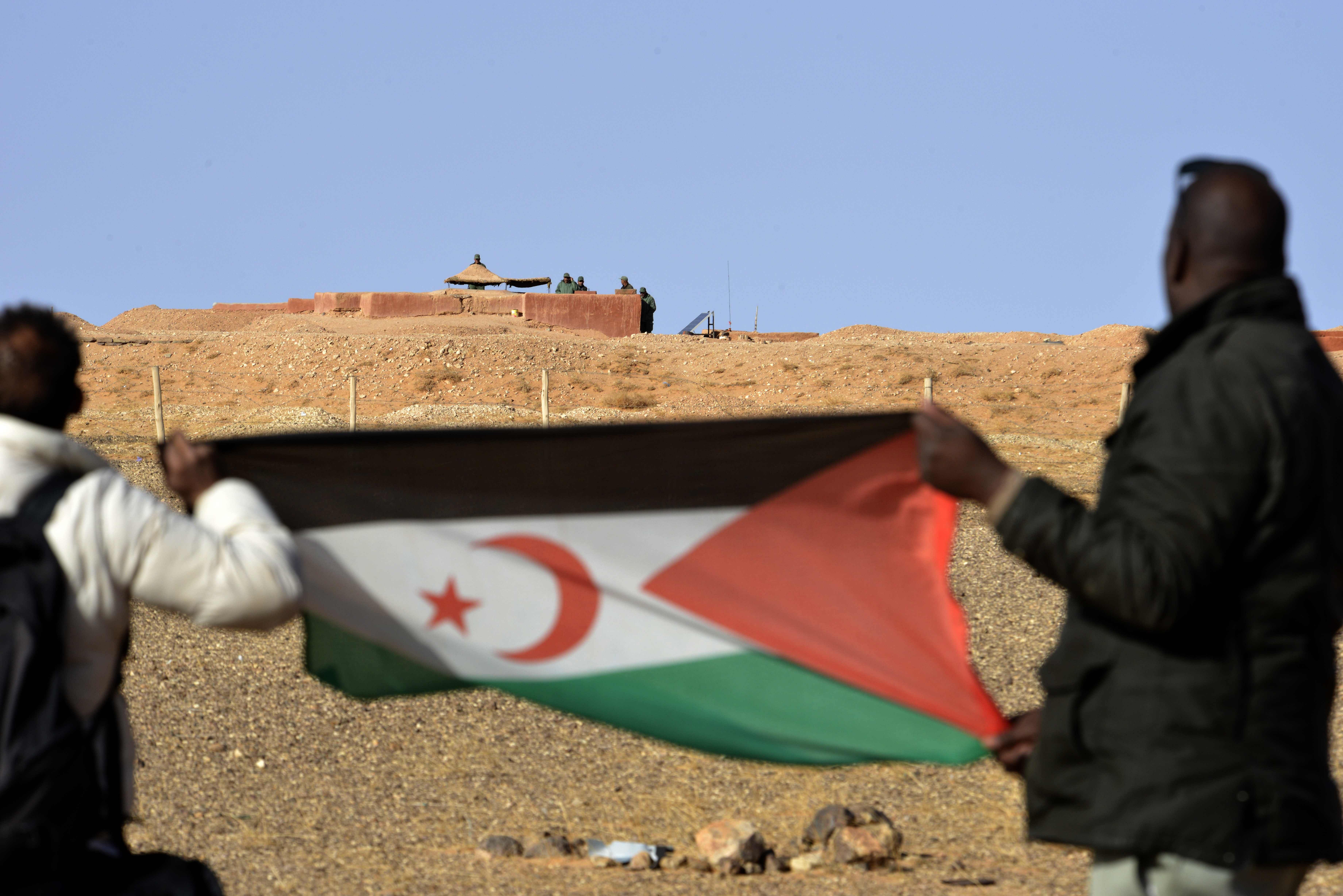 A Saharawi man holds up a Polisario Front flag in the Al-Mahbes area in the Polisario controlled Western Sahara, about 1.000 north west the border crossing of Guerguera. - Morocco announced on November 13, 2020 that its troops have launched an operation in no man's land on the southern border of the Western Sahara to end "provocations" by the pro-independence Polisario Front. Credit: AFP Photo