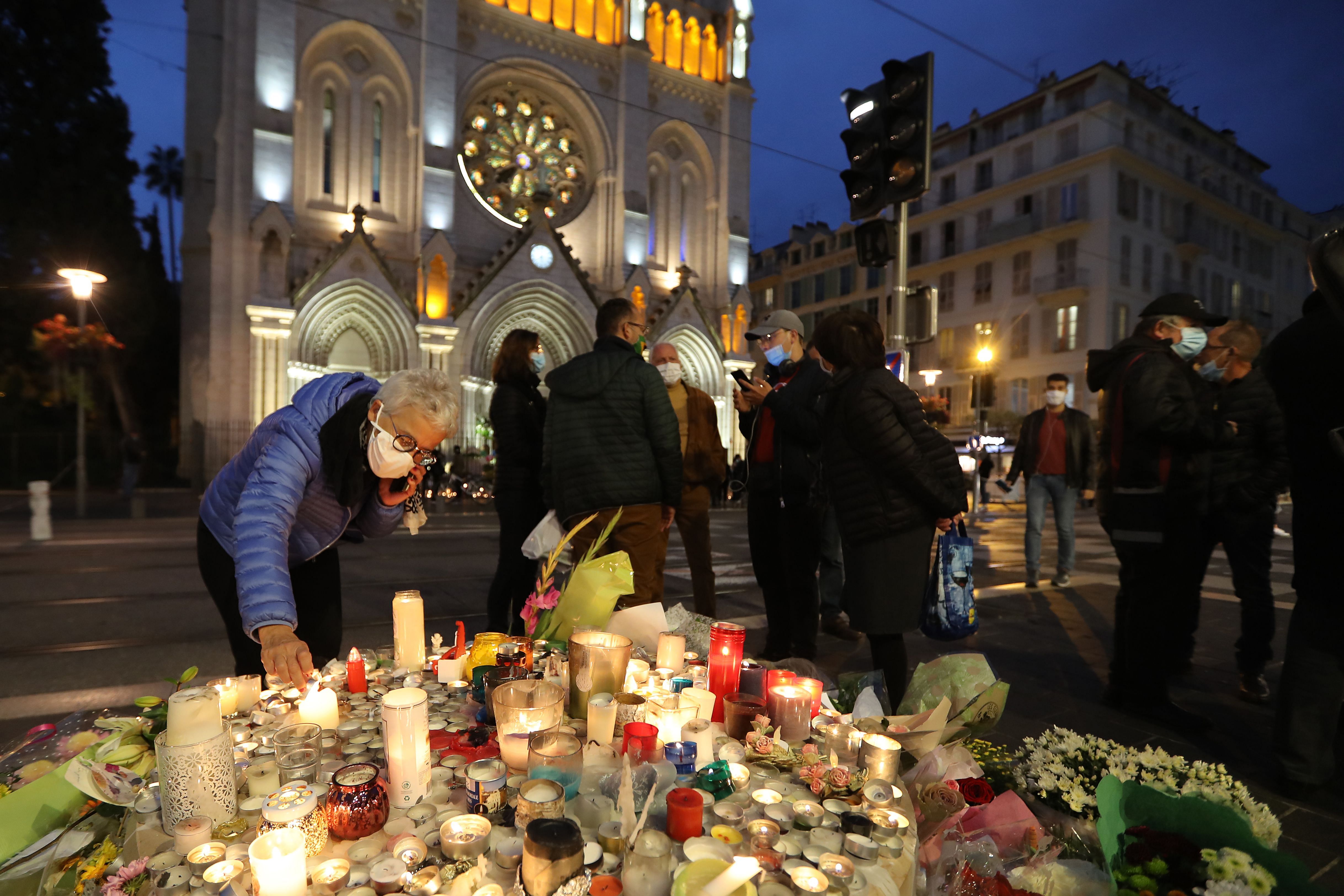 A woman lights a candle outside Notre-Dame de l'Assomption Basilica in Nice on October 31, 2020, to pay tribute to the victims two days after a knife attacker killed three people, cutting the throat of two, inside the church of the French Riviera city, and police arrest a young Tunisian migrant from Sfax who arrived in Europe only last month, according to French prosecutors. - The killings came two weeks after a French teacher was decapitated outside his school north of Paris by a suspected Islamist extremist. The teacher had shown his pupils cartoons of the Prophet Mohammed during a lesson on freedom of speech. Credit: AFP Photo