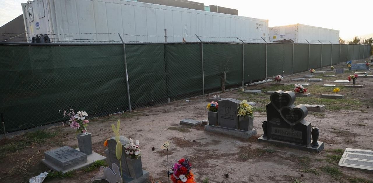 Refrigerated temporary morgue trailers are parked in a parking lot at the El Paso County Office of the Medical Examiner, next to a cemetery, amid a surge of Covid-19 cases in El Paso. Credit: AFP.