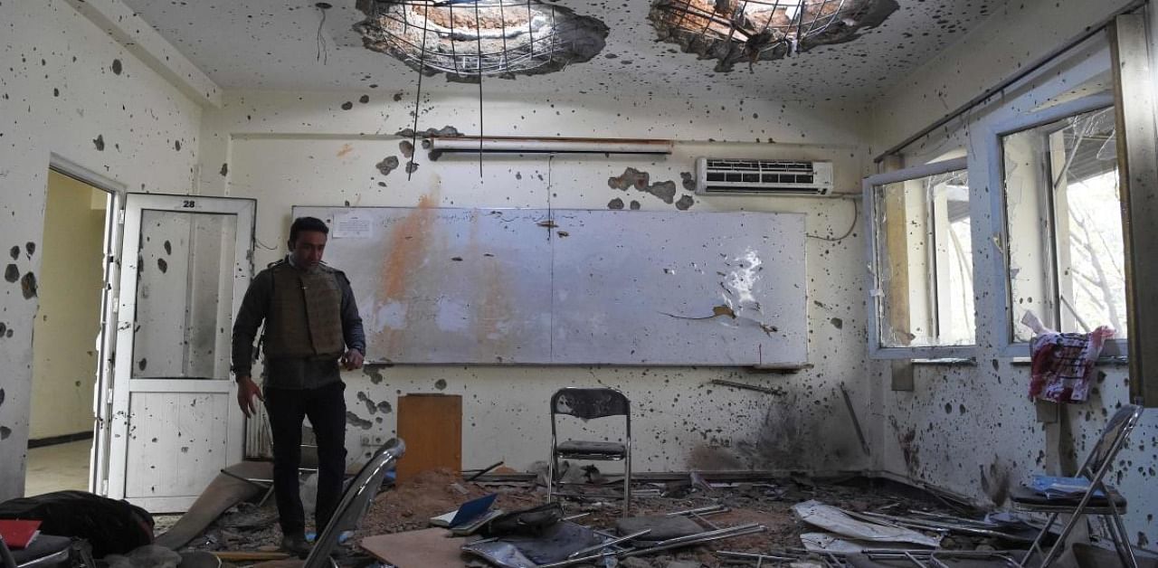 A journalist walks inside of a damaged class of the National Legal Training center, a day after gunmen stormed Kabul university. Credit: AFP.