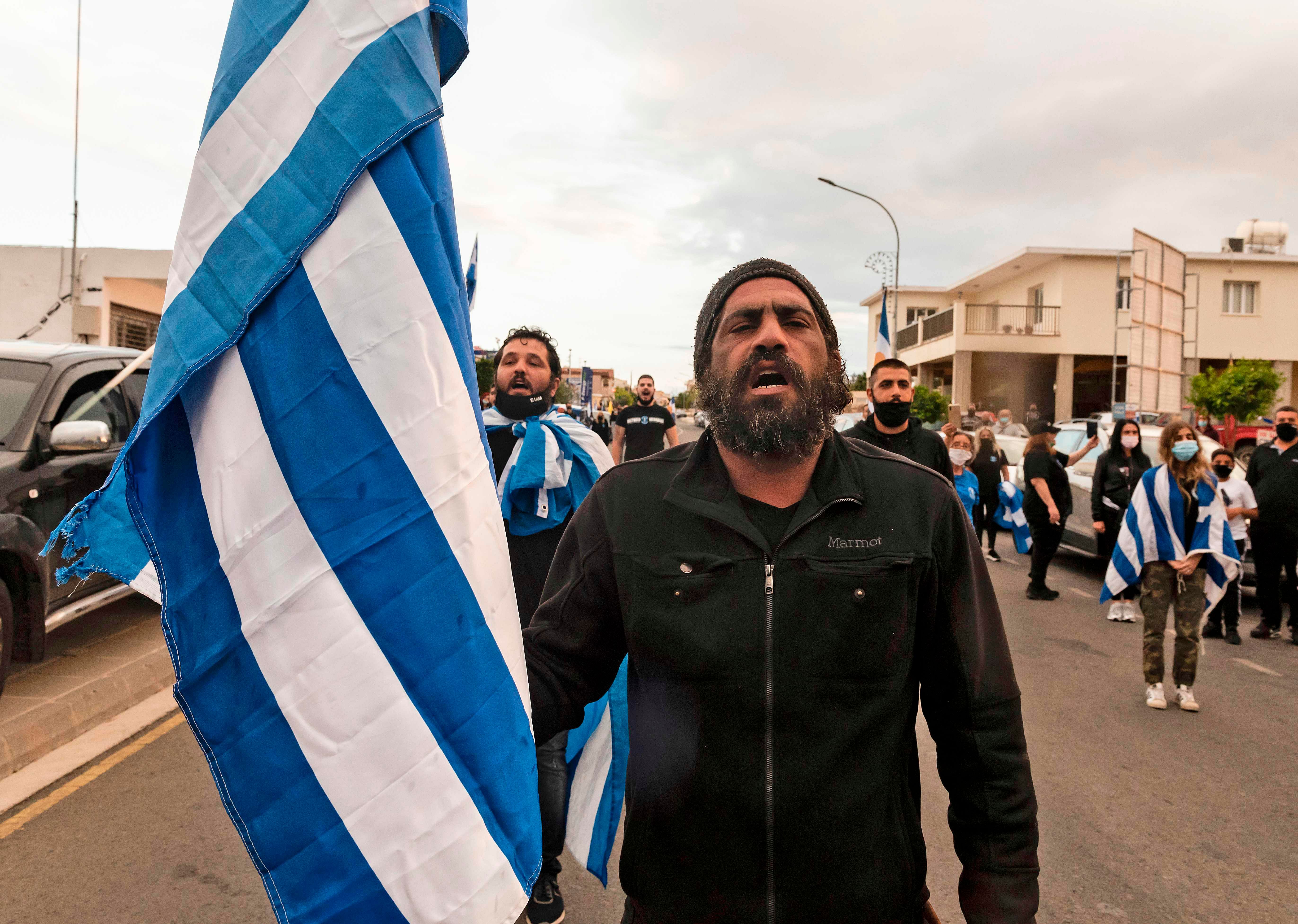 Members and supporters of Cypriot far-right National Popular Front party (ELAM) carry Greek flags as they rally at the Dherynia check point, to protest the official visit of the Turkish President to the fenced-off eastern town of Varosha, in the Turkish-occupied north of the divided Mediterranean island, on November 15, 2020. - Turkish President Recep Tayyip Erdogan said he favours a permanent division of Cyprus into two states, during a visit to the breakaway Turkish-held north decried as a "provocation" by the internationally recognised Greek-speaking south. Credit: AFP Photo
