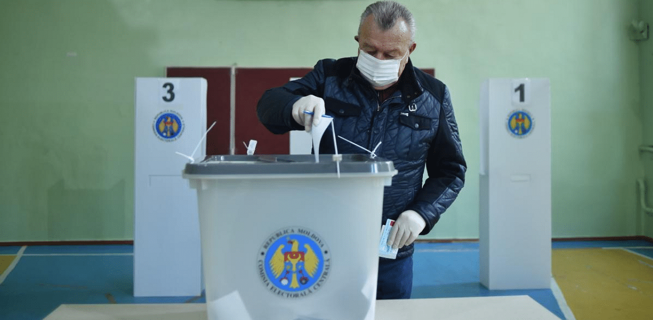 A man wearing a face mask and gloves casts his ballot at a polling station during the second round of Moldova's presidential election in the town of Varnita at Moldova. Credit: AFP Photo