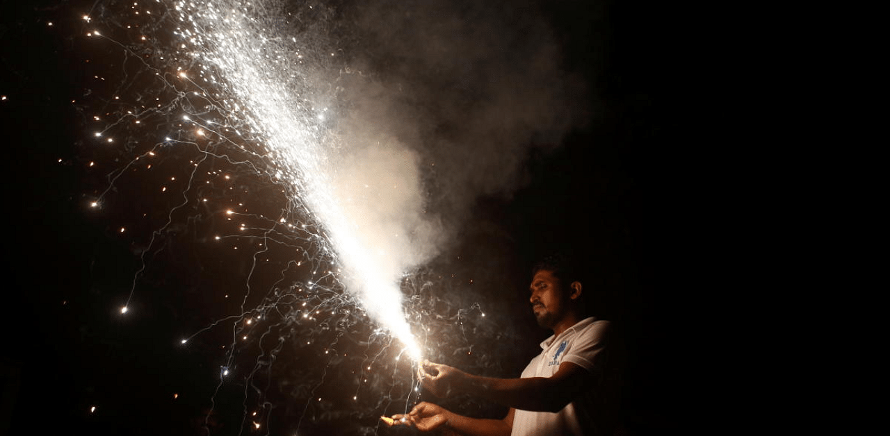Man holds a firecracker as it burns during Diwali in Mumbai. Credit: Reuters Photo