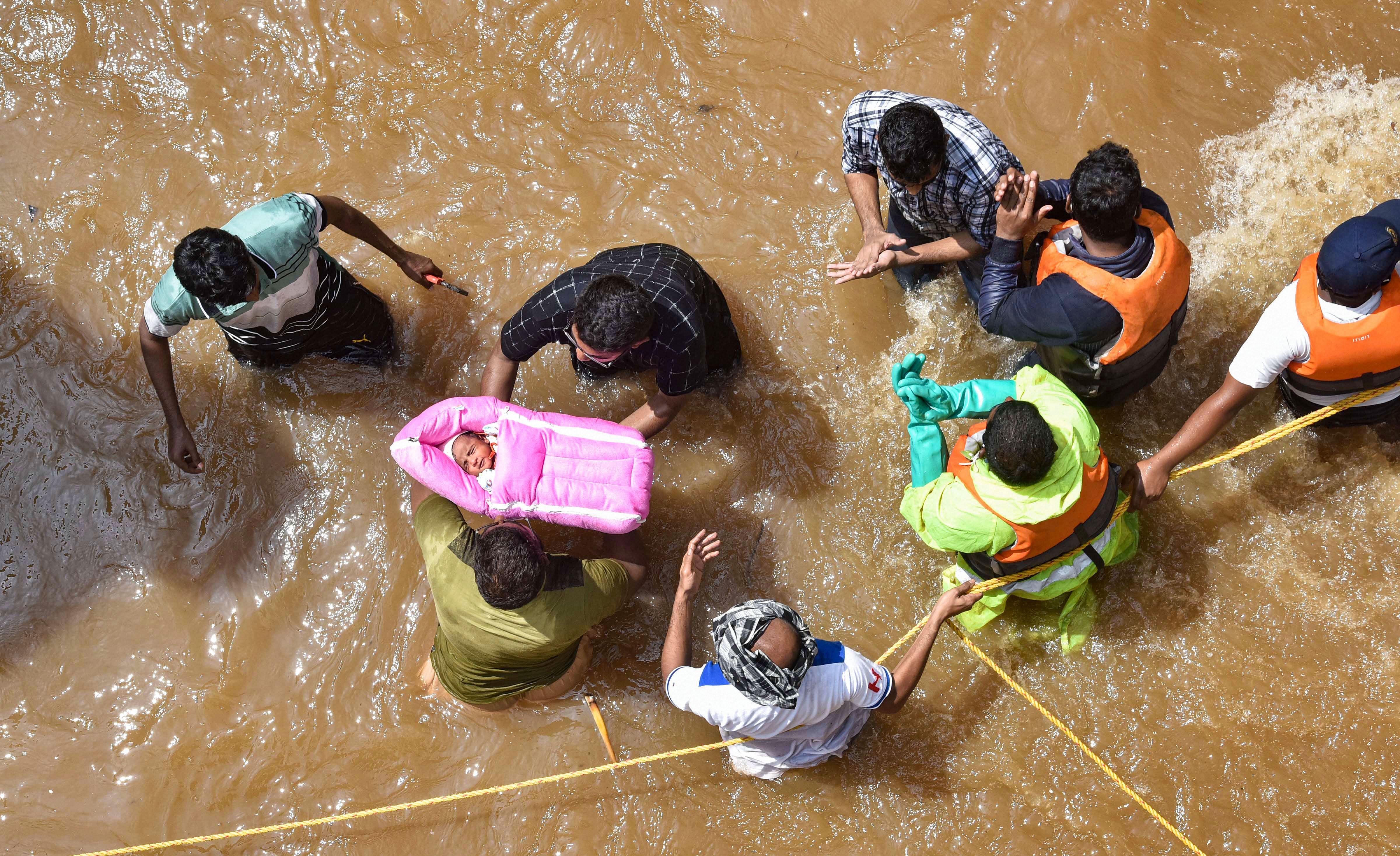 GHMC personnel carry an infant during an operation to move flood-affected people to a safer place, at Hafiz Baba Nagar in Hyderabad, Sunday, Oct. 18, 2020. Credit: PTI Photo