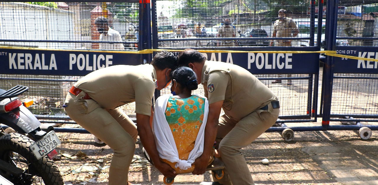 Picture of woman with disability being lifted by two police personnel at Kochi that was shared by Kerala Police's social media wing. Credit: Special Arrangement