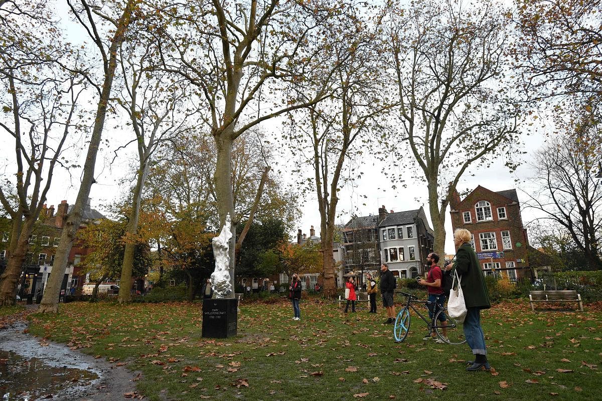   People look at and photograph a new sculpture honouring 18th century British author and feminist icon Mary Wollstonecraft by British artist Maggi Hambling after it was unveiled in north London's Newington Green on November 10, 2020 close to where Wollstonecraft lived and worked. - The artwork, cast in silvered bronze, was unveiled after over a decade of local campaigning and fundraising. Wollstonecraft, born in 1759 and died in 1797, was one of the founding feminist philosophers and author of the seminal text 'A Vindication of the Rights of Woman'. Credit: JUSTIN TALLIS / AFP
