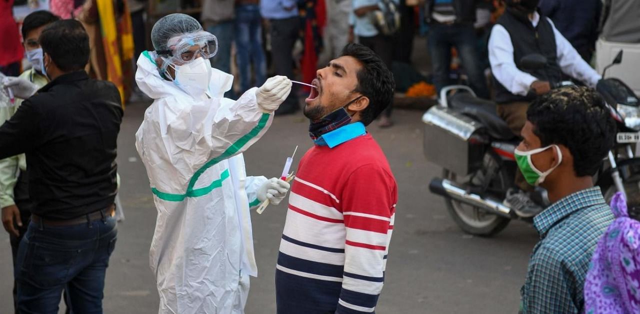 A medical worker collects a swab sample from a man for a RT-PCR test for the Covid-19 coronavirus along a street in New Delhi. Credit: AFP.