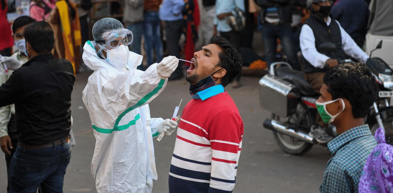 A medical worker collects a swab sample from a man for a RT-PCR test for the Covid-19 coronavirus along a street in New Delhi. Credit: AFP Photo