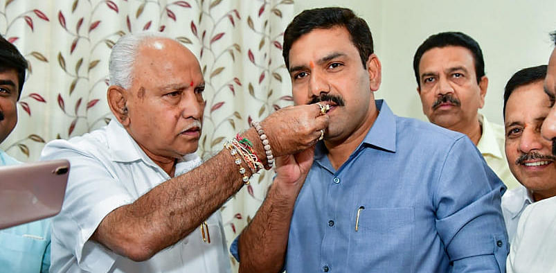 Karnataka Chief Minister BS Yediyurappa offer sweets to son BY Vijayendra. Credit: PTI file photo