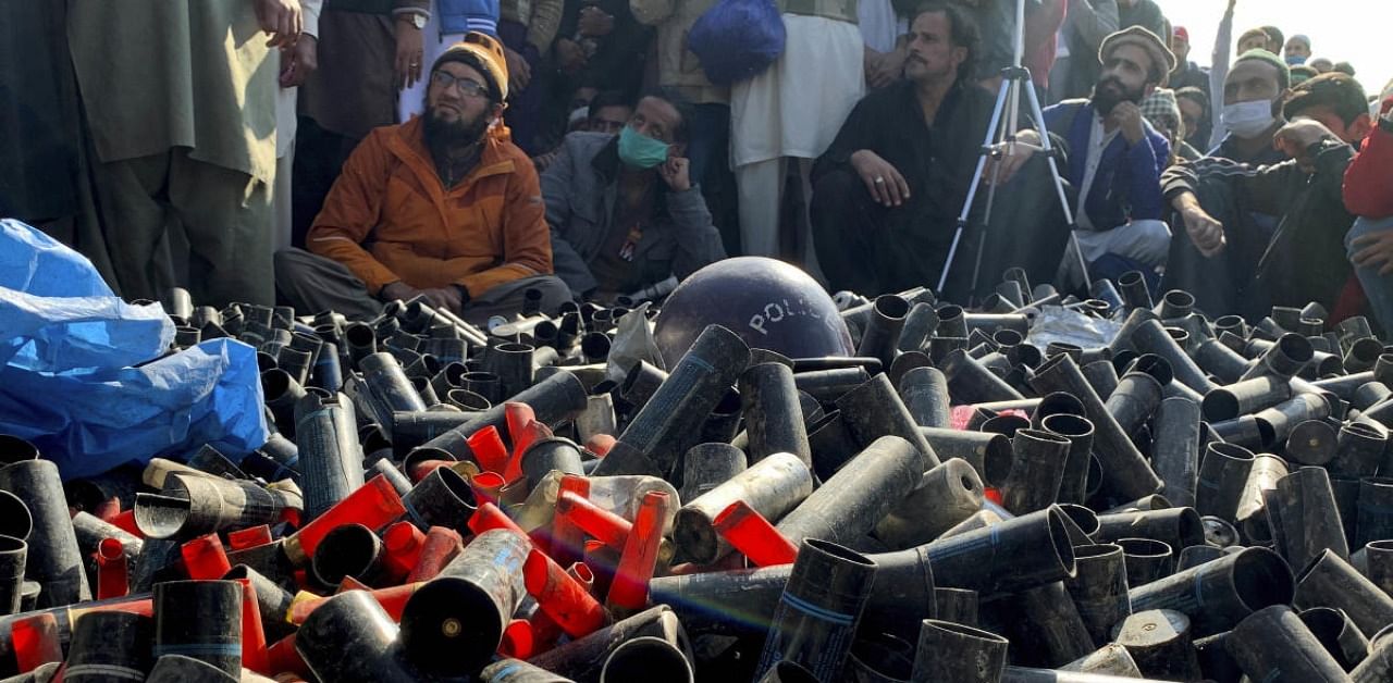 Supporters of 'Tehreek-e-Labaik Pakistan, a religious political party, sit beside empty tear gas shells fired by police to stop them enter in to capital during an anti-France rally. Credit: AP/PTI Photo