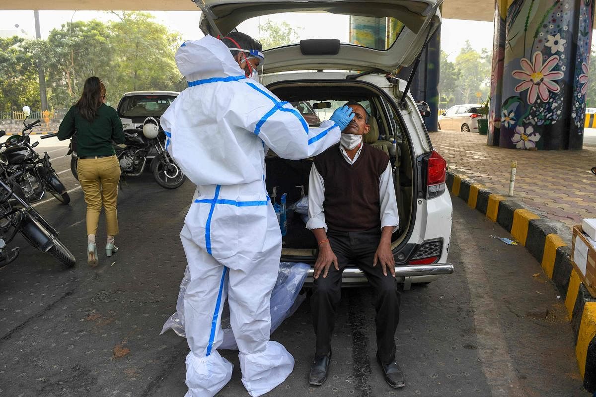 A medical worker wearing protective gear collects a nasal swab sample from a man for a Rapid Antigen Test (RAT) for the Covid-19 coronavirus as Noida authorities started conducting random coronavirus testing on commuters arriving from Delhi at Delhi-Uttar Pradesh state border in Noida. Credit: AFP