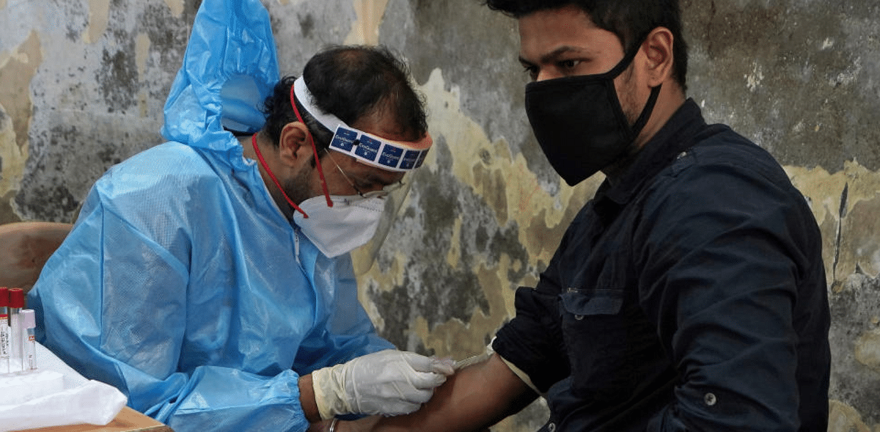 A healthcare worker wearing a protective gear collects blood sample from a man, who has recovered from the coronavirus disease (COVID-19), during a plasma donation camp inside a classroom at a slum in Mumbai, India, July 24, 2020. Credit: Reuters Photo
