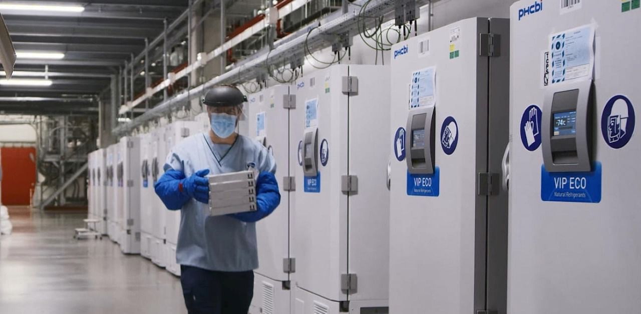 A worker passes a line of freezers holding coronavirus disease vaccine candidate BNT162b2 at a Pfizer facility in Puurs, Belgium. Credit: Reuters Photo