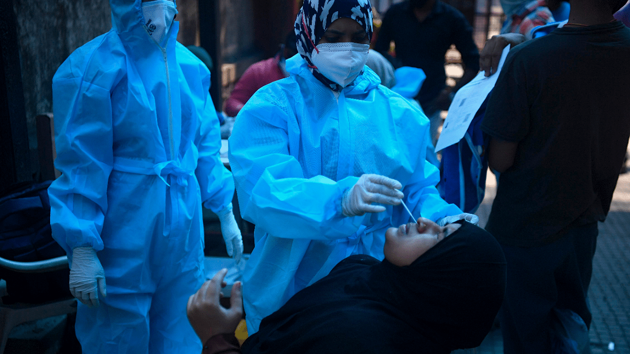 A health worker collects a swab sample from a woman at a Covid-19 coronavirus screening site in Mumbai. Credit: AFP Photo