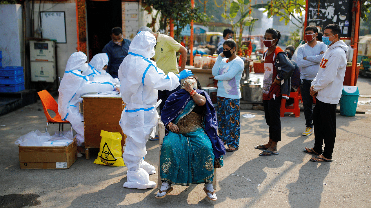 A healthcare worker wearing personal protective equipment (PPE) collects a swab sample from a woman amidst the spread of the coronavirus. Credit: Reuters Photo
