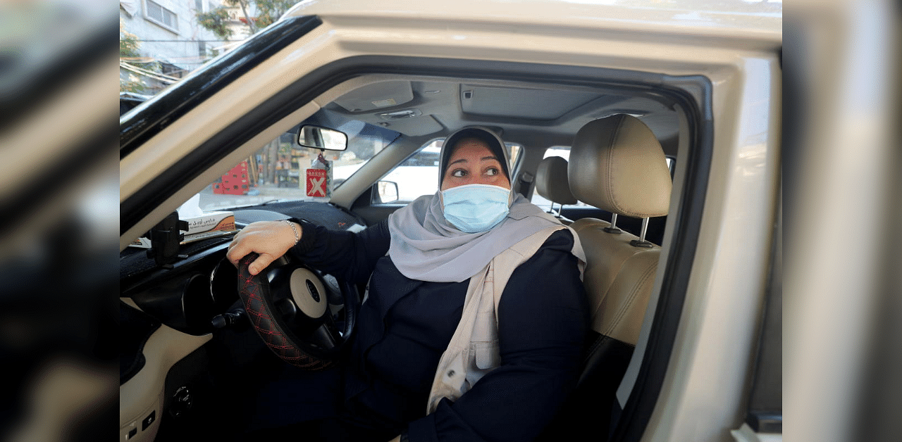 Palestinian woman Naela Abu Jibba, who started a women-only taxi service in Gaza Strip, sits behind the wheel of her vehicle at Beach refugee camp in Gaza City November 17, 2020. Picture taken November 17, 2020. Credit: Reuters Photo