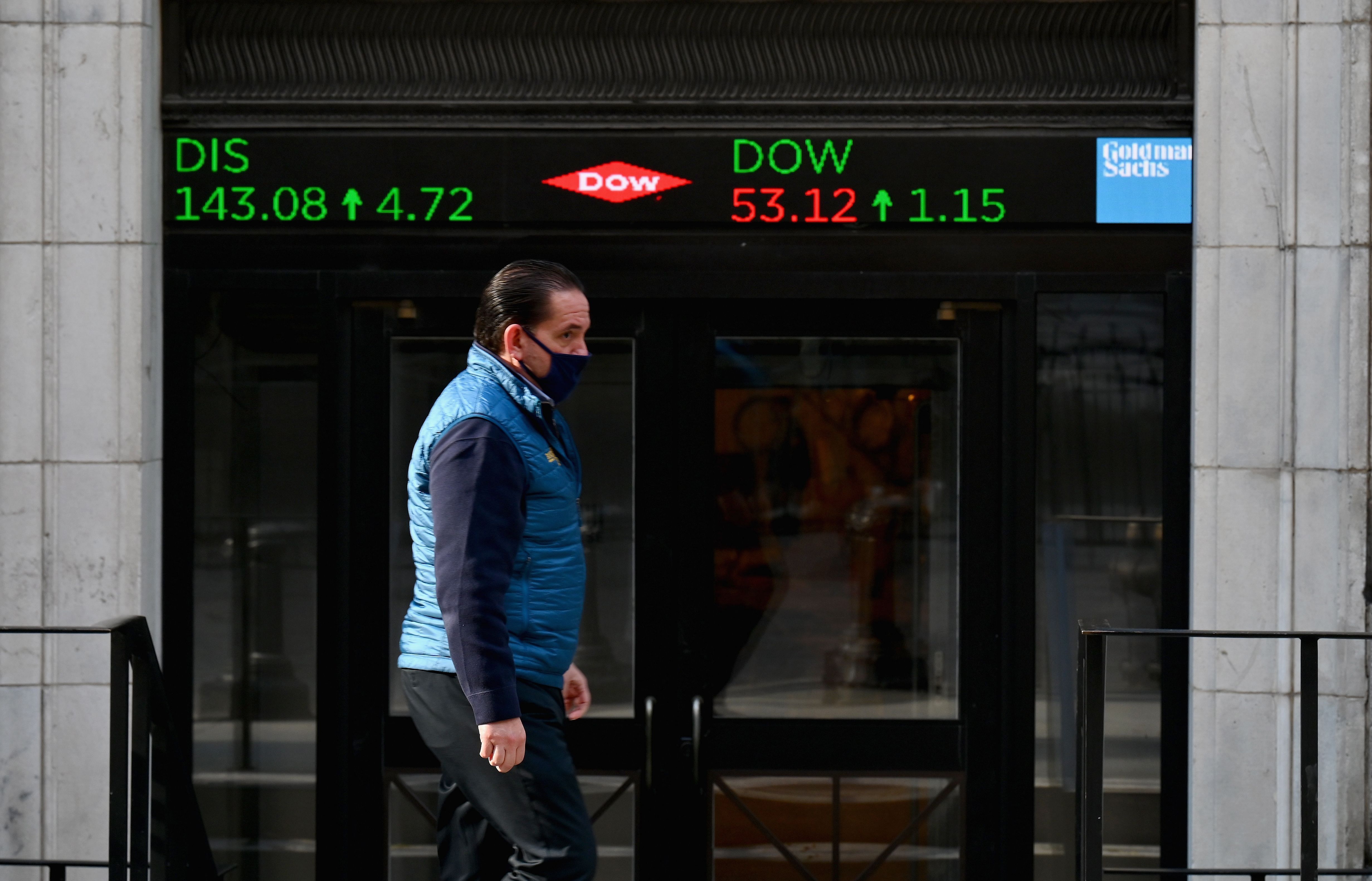 A stock trader walks past the New York Stock Exchange (NYSE) at Wall Street. Credit: AFP Photo