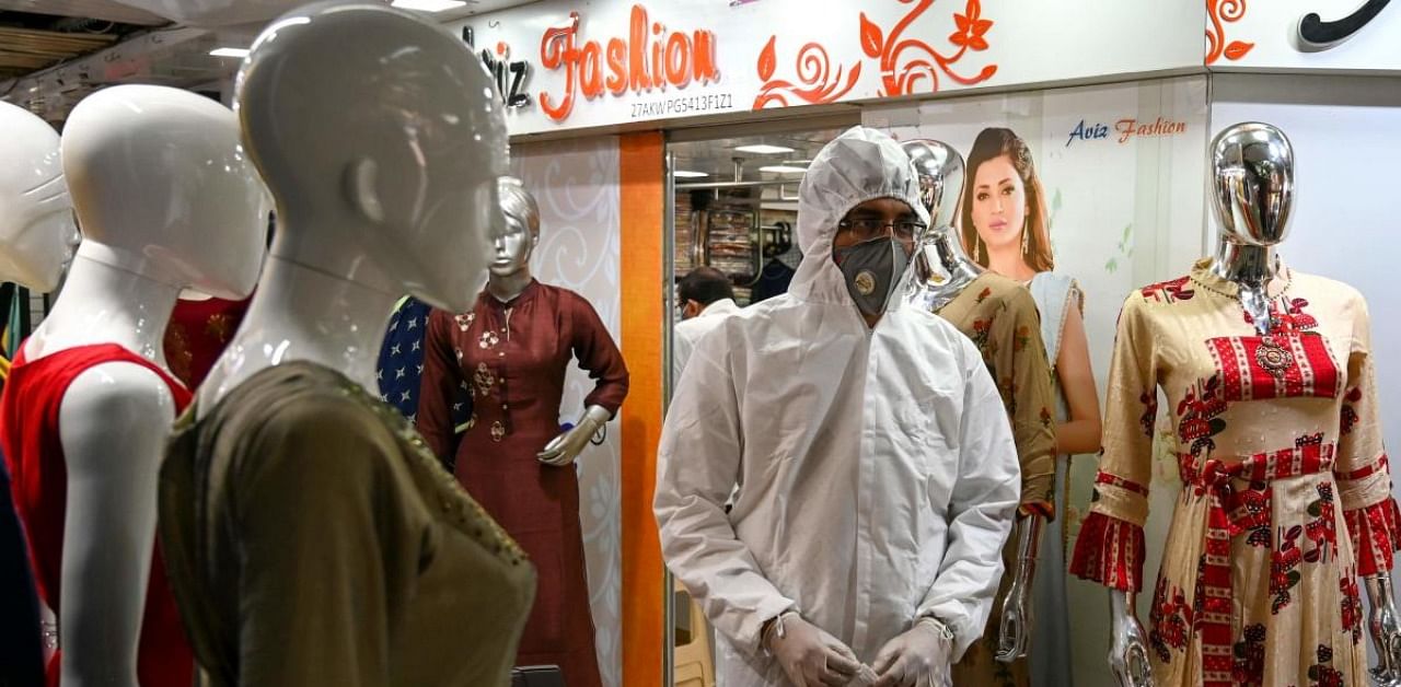 A health worker wearing protective gear waits to collect swab samples from people during a medical screening for the Covid-19 coronavirus at a garment wholesale market in Mumbai on November 20, 2020. Credit: AFP Photo