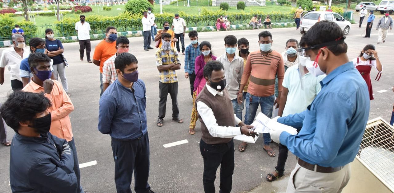 Health department officials distribute Covid-19 test reports, near the Rangacharlu Town Hall in Mysuru recently. Credit: DH file photo.