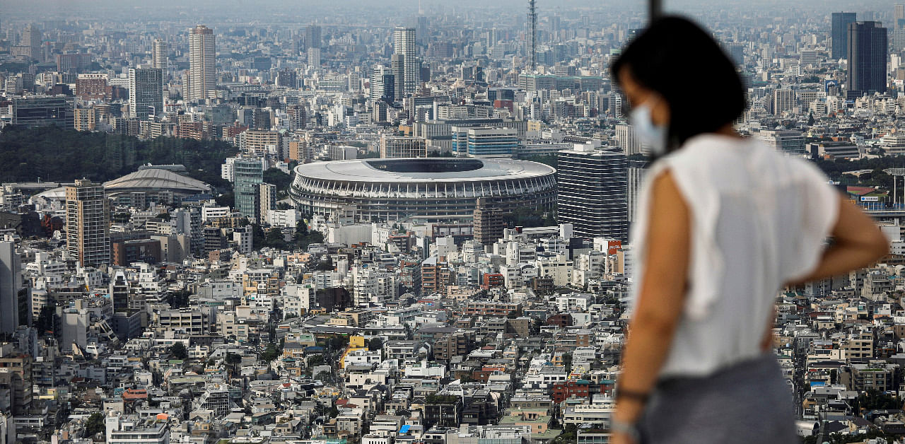 The National Stadium, the main stadium of Tokyo 2020 Olympics and Paralympics, is seen past a visitor wearing a protective face mask amid the coronavirus disease. Credit: Reuters Photo