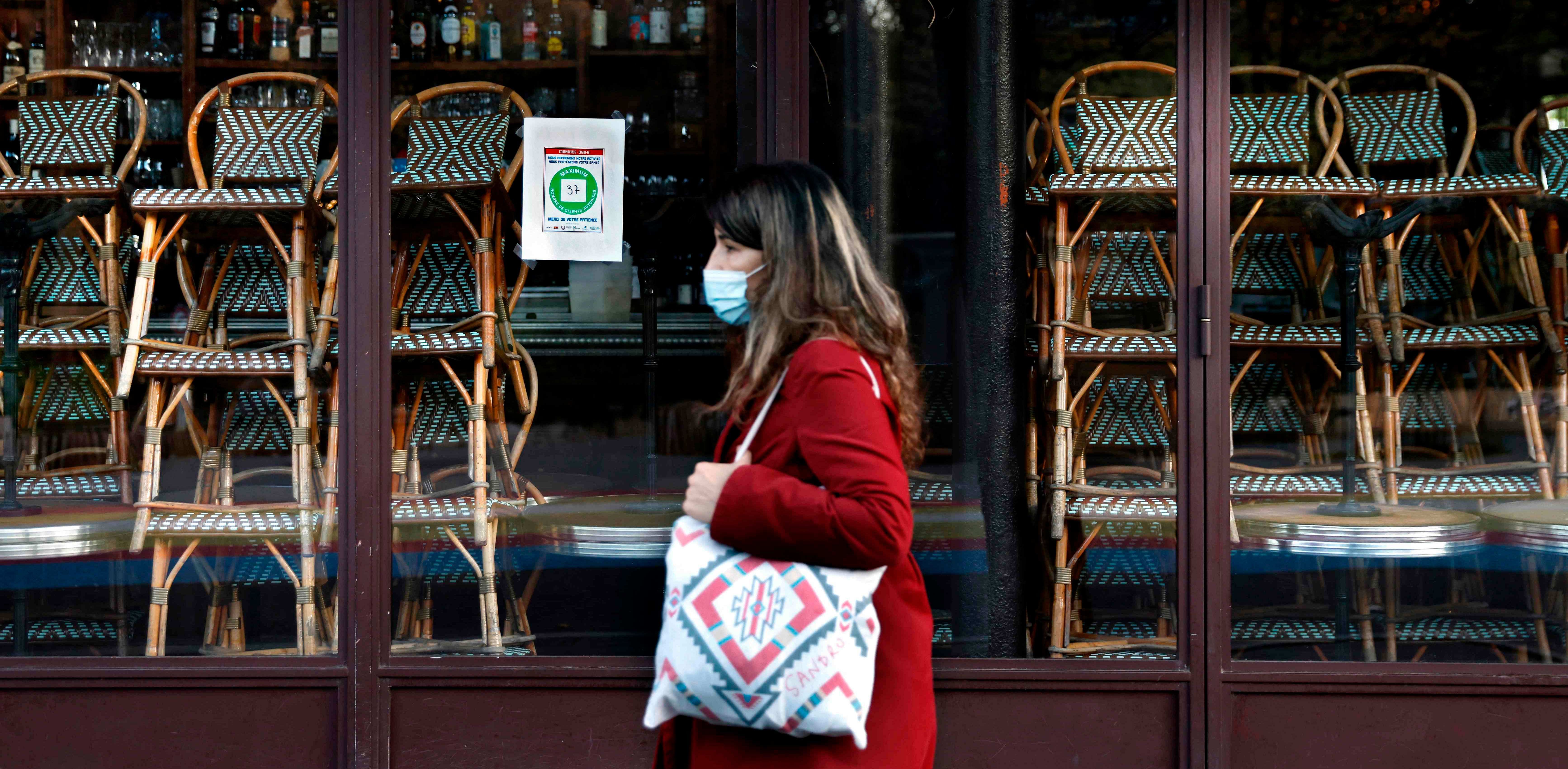 A woman walks past a closed restaurant in Paris on November 18, 2020, amid a second lockdown in France aimed at containing the spread of Covid-19 pandemic caused by the novel coronavirus. Credit: AFP