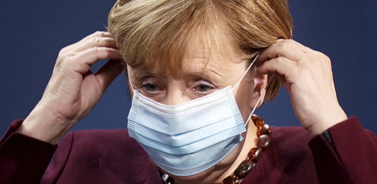 German Chancellor Angela Merkel puts on her face mask after holding a joint news conference with Finance Minister Olaf Scholz after a virtual G20 summit meeting. Credit: AP/PTI.