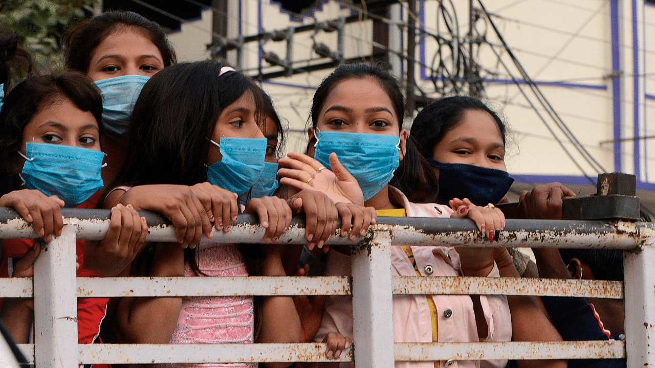 People wear face masks as they stand along a sidewalk in Siliguri. Credit: AFP Photo