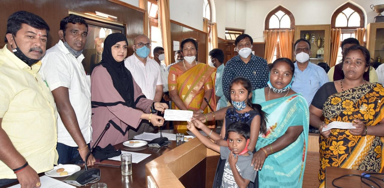 Mayor Tasneem hands over a compensation cheque to the members of a civic worker, who died as Covid warrior, in Mysuruon Monday. Credit: DH photo.