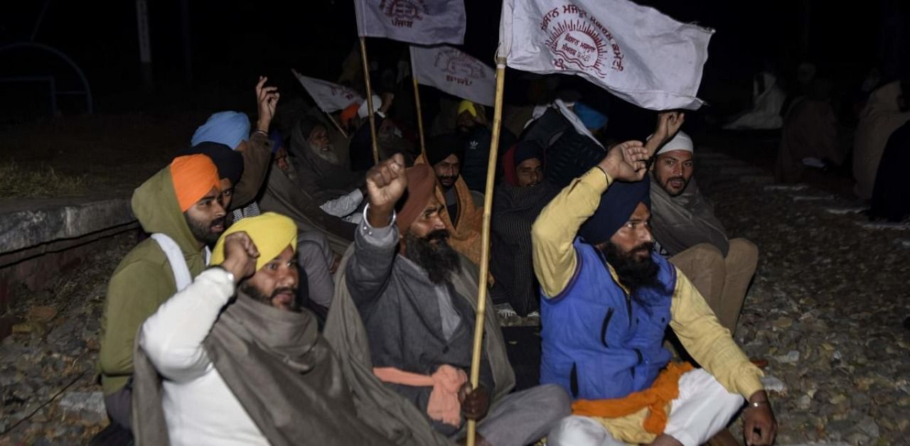 Farmers shout slogans as they block a railway track during a protest at the Jandiala railway station before dawn on the outskirts of Amritsar. Credit: AFP.