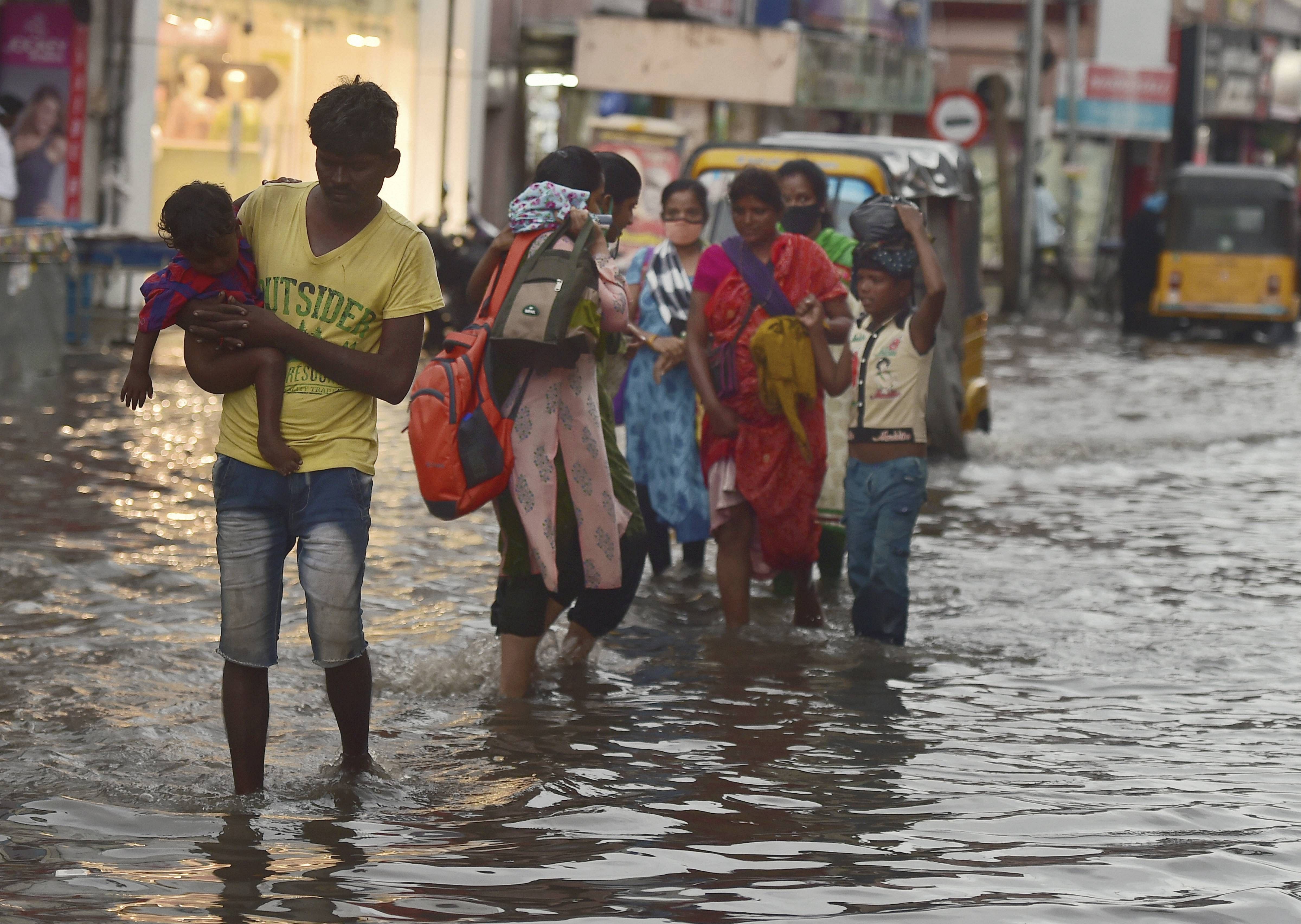 Pedestrians wade through a waterlogged road during heavy rain triggered by Cyclone Nivar, in Chennai, Tuesday, Nov. 24, 2020. Credit: PTI Photo