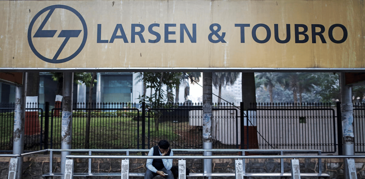 A man waits at a bus-stop with an advertisement of Larsen & Toubro outside the company's manufacturing unit in Mumbai. Credit: Reuters file photo. 