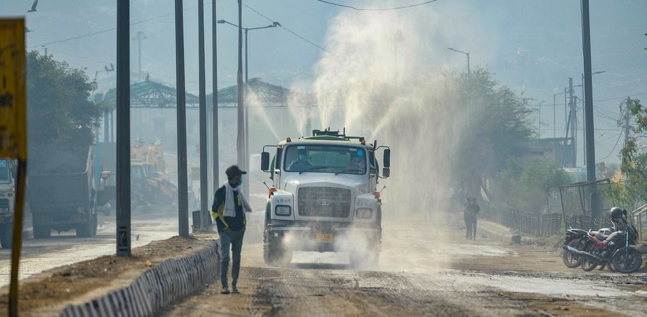 An EDMC vehicle sprinkles water over a road at Ghazipur to contain pollution, in New Delhi. Credit: PTI Photo