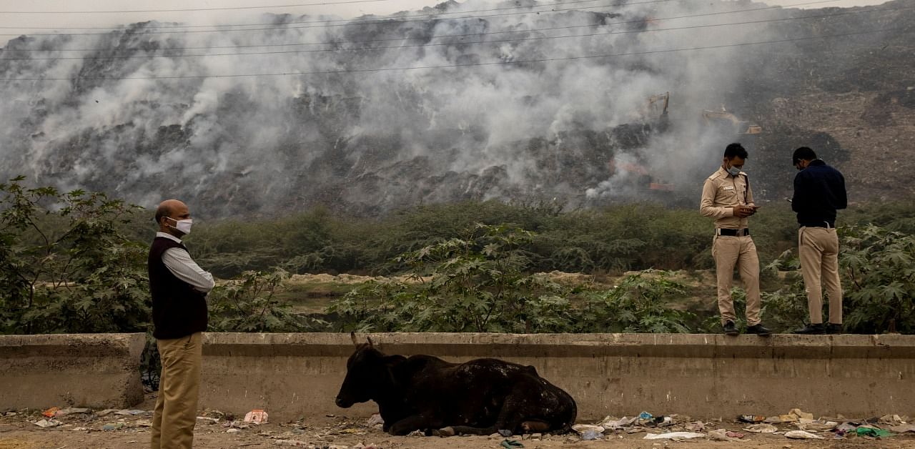 Members of Delhi government anti-pollution squad report the status of the fire as smoke billows from burning garbage at the Ghazipur landfill site in New Delhi. Credit: Reuters Photo