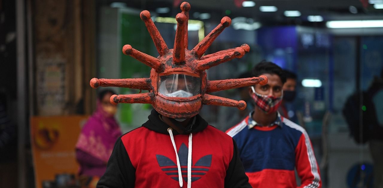 A civil defence volunteer wearing a Covid-19-themed helmet holds a placard as he takes part in an awareness campaign at a market in New Delhi on November 25. Credit: AFP Photo