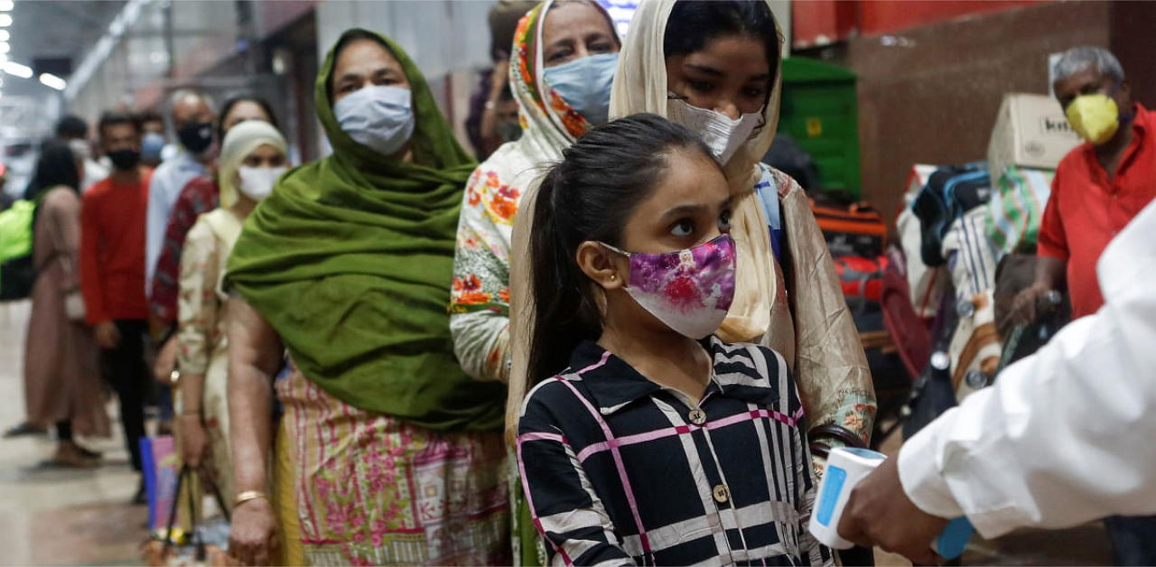 Passengers wait in line to get their temperature checked at a railway station, amid the spread of the coronavirus disease in Mumbai. Credit: Reuters