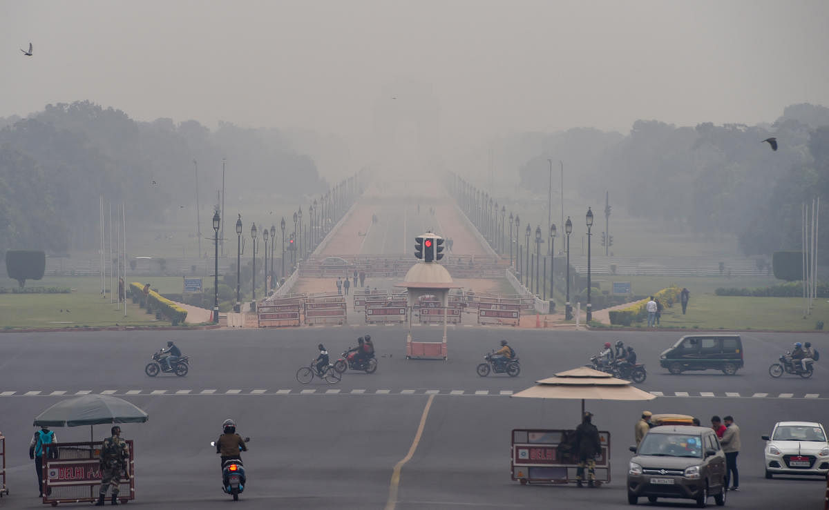 Vehicles ply at Vijay Chowk amid low visibility due to smog, in New Delhi. Credit: PTI